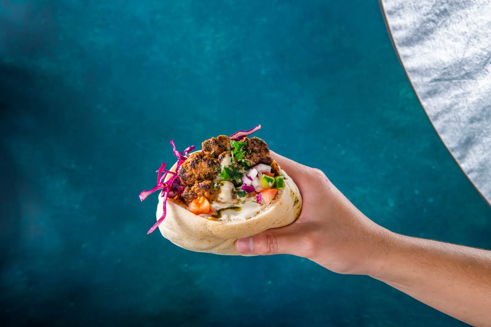 A ZHUG falafel pita held in one hand, ready to eat